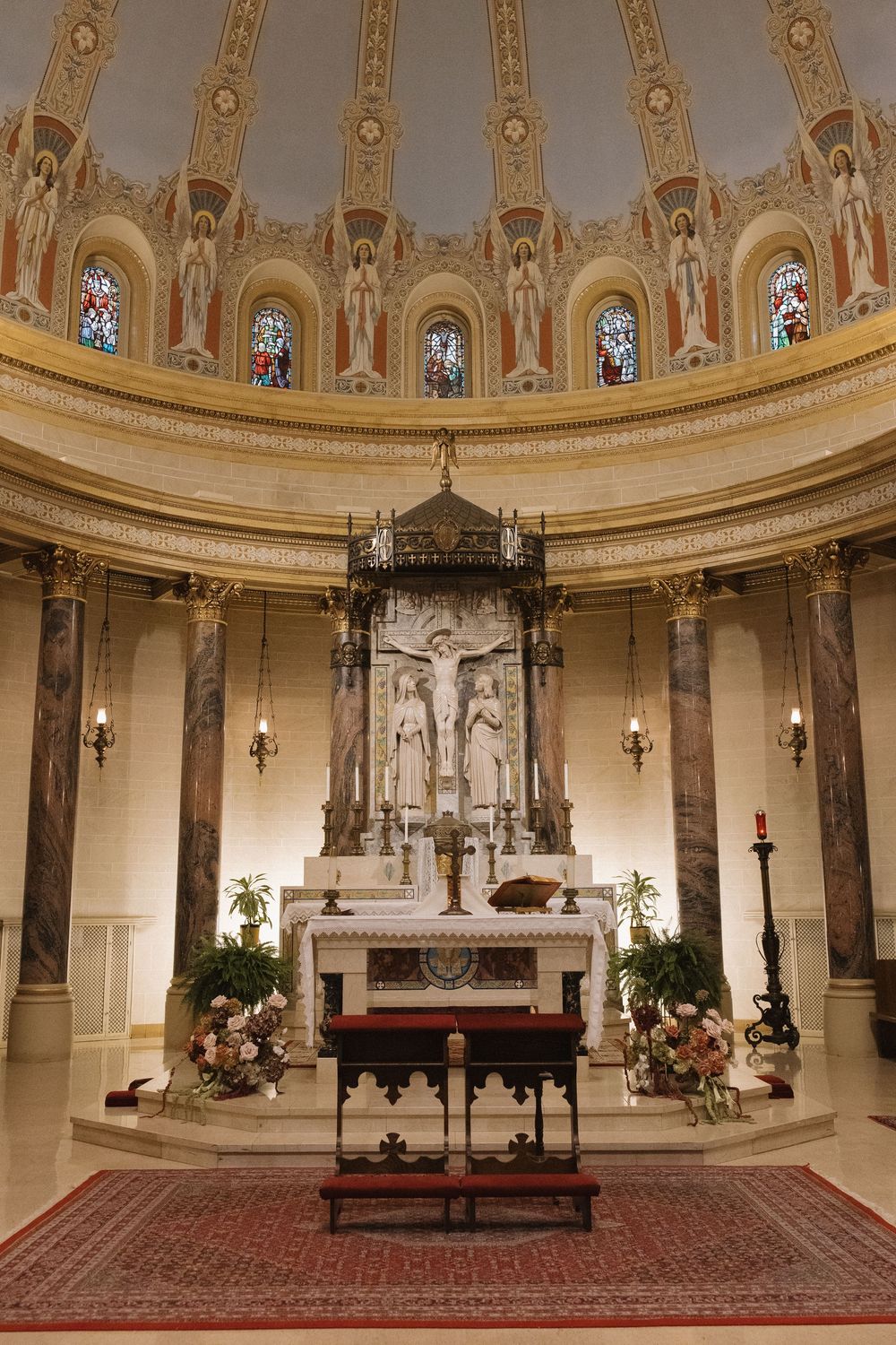 Interior view of an ornate church sanctuary with domed ceiling, stained glass windows and traditional altar setup.