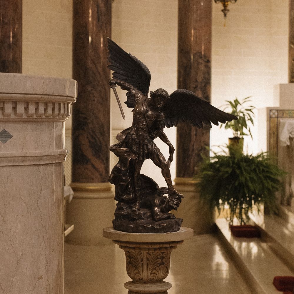 Museum hallway with marble columns and bronze sculptures displayed on pedestals along the corridor.