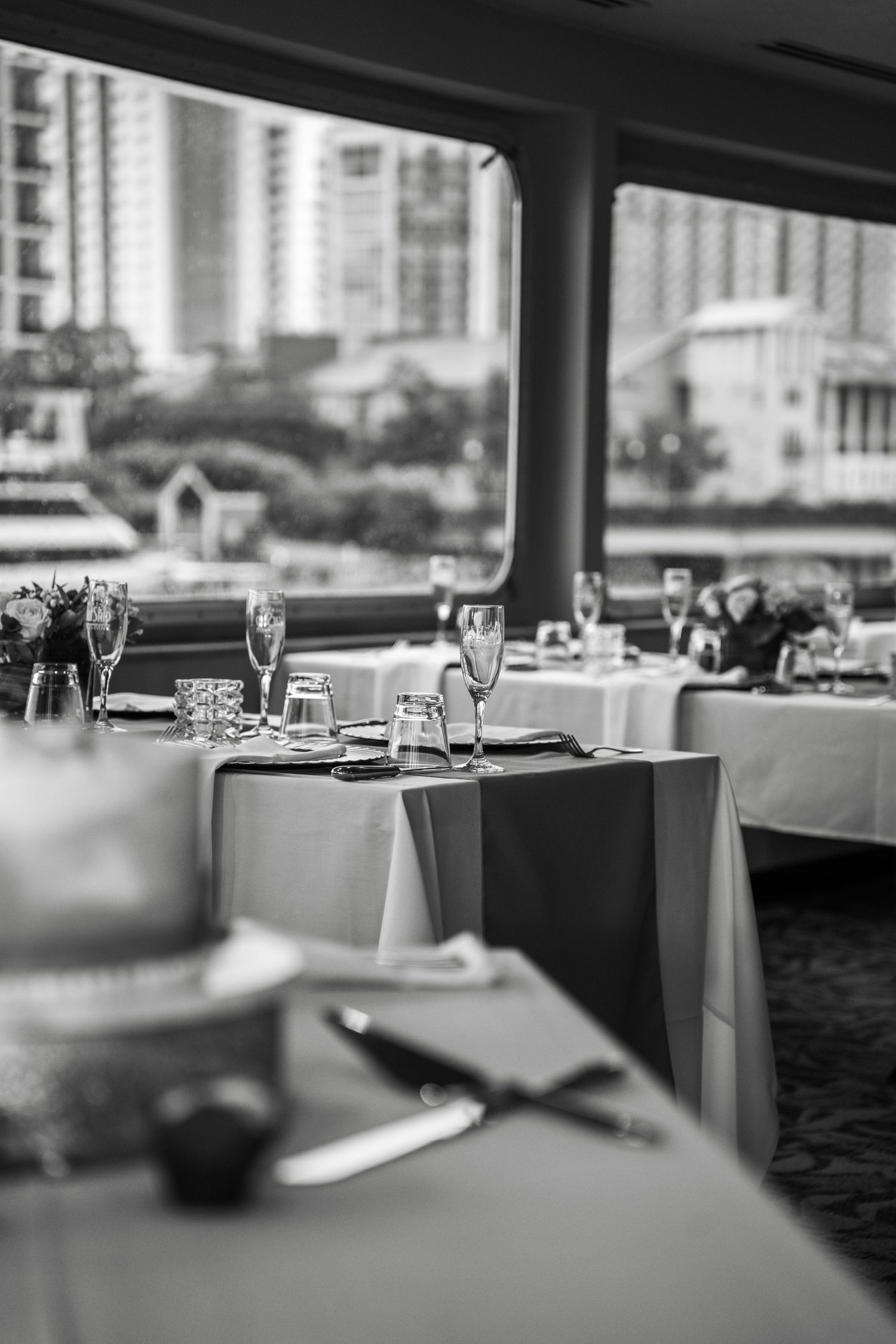 Elegant restaurant dining tables set with white linens and wine glasses in a modern upscale setting.
