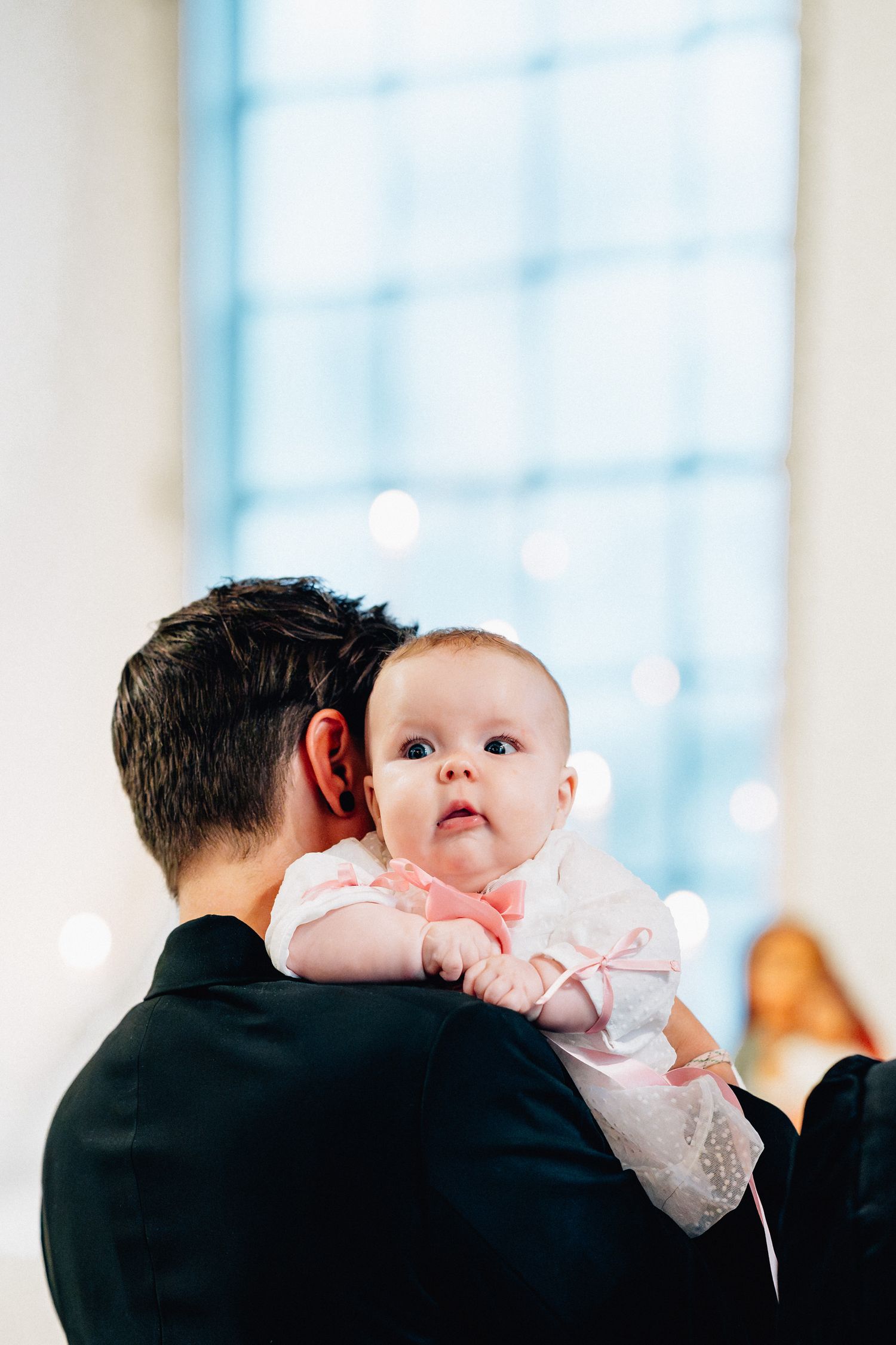 En bebis tittar över sin mammas axel under dopet i kyrkan.