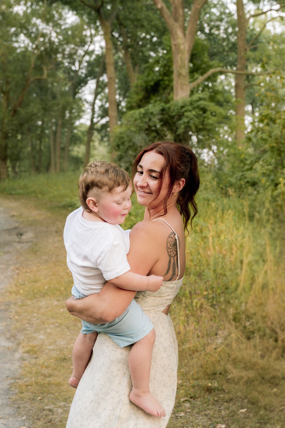 A tender moment captured outdoors between a parent and child against a natural wooded backdrop.