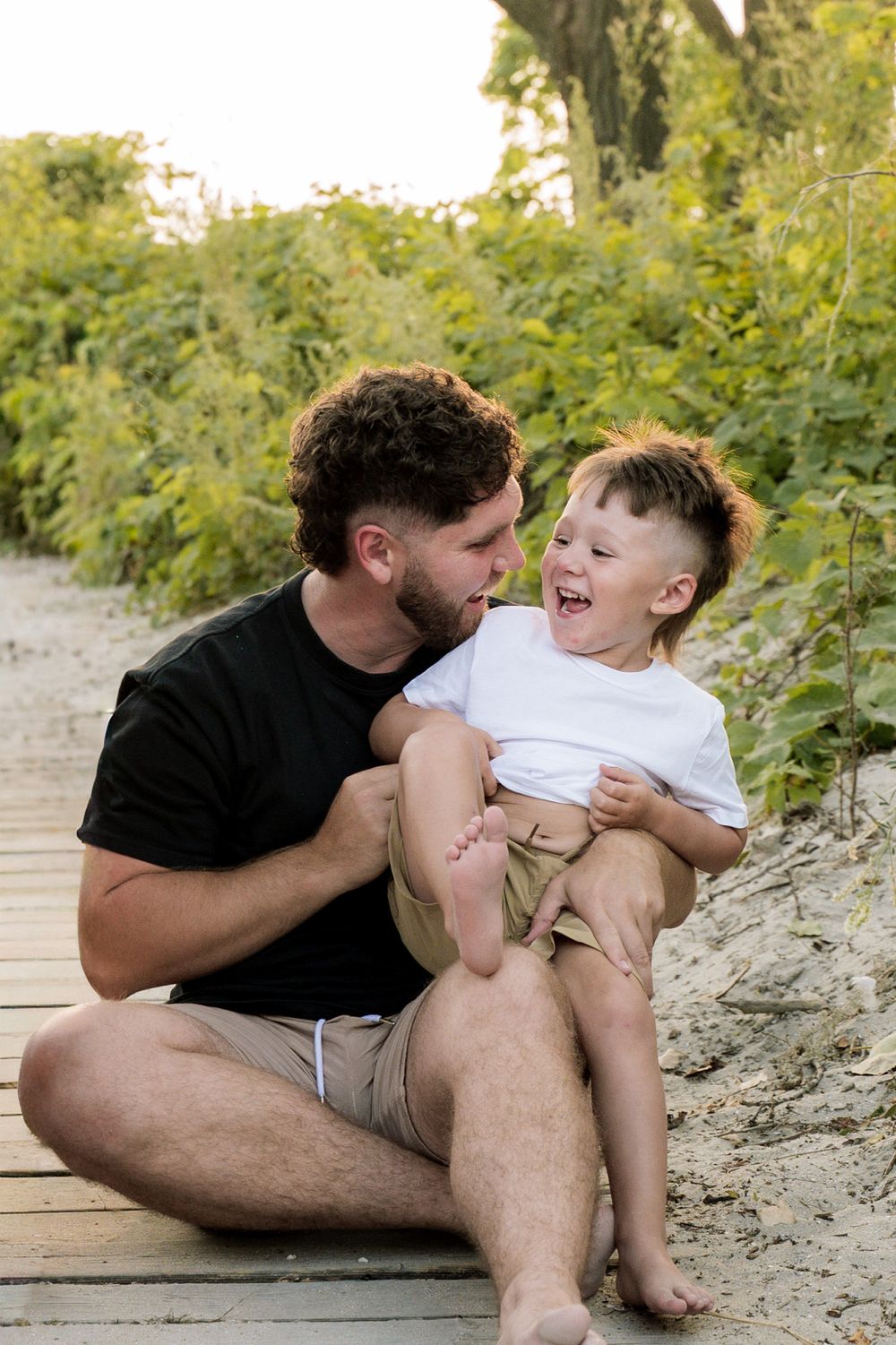 Playful moments shared between parent and child on a rocky riverbank during golden hour.
