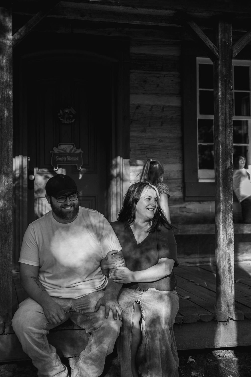 People gathered on a rustic wooden porch in black and white, creating a nostalgic vintage scene.