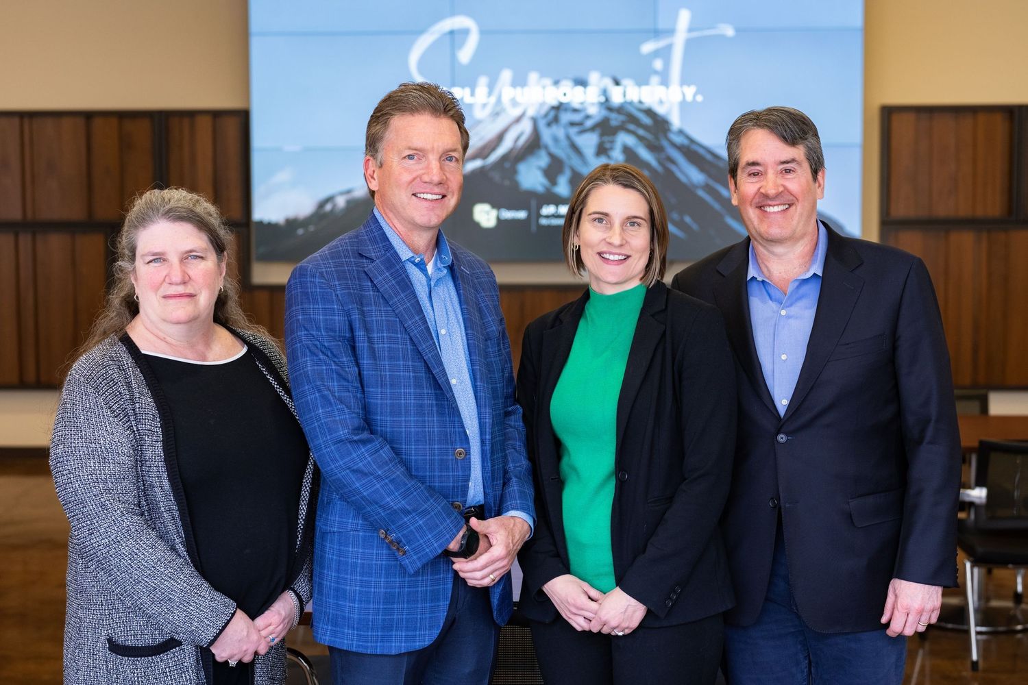 Professional group photo with mountain backdrop and business attire.
