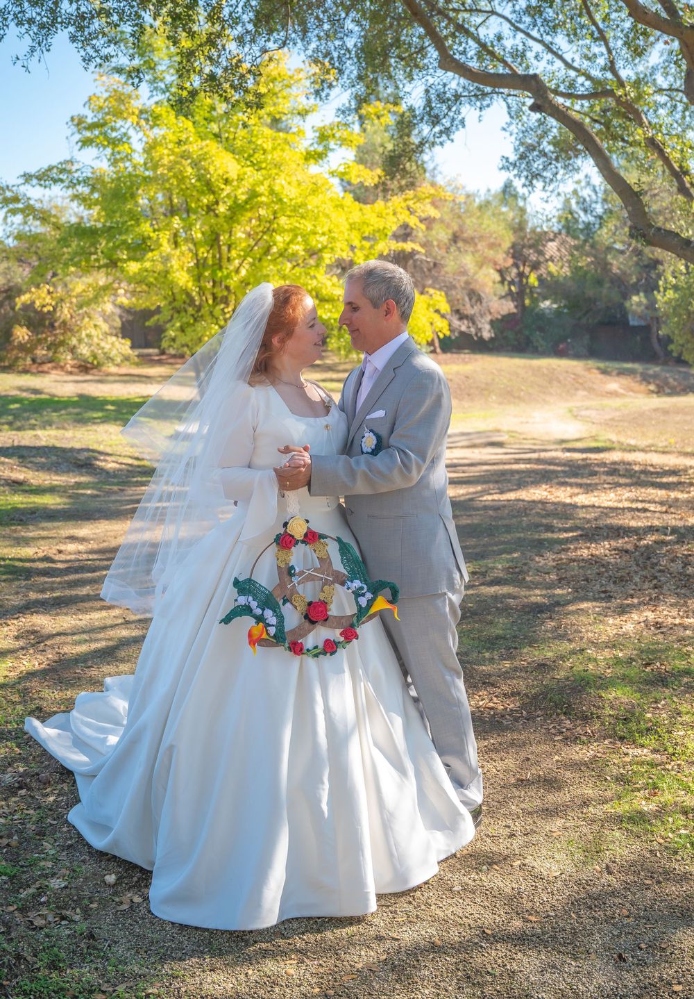 A couple in wedding attire shares romantic moments under golden autumn trees in a natural outdoor setting.
