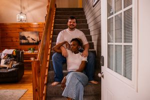 Couple sitting together on wooden porch steps of a rustic cabin during sunset.