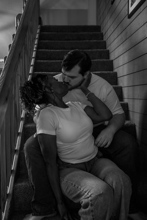 A tender moment captured in black and white as two people share an emotional embrace on stairs.