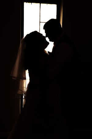 Four silhouetted figures in backlit window frames create a dramatic contrast against bright natural light.