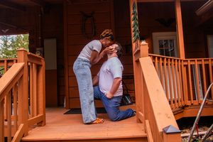 A person in blue jeans works on installing wooden deck railing posts and balusters during a home improvement project.