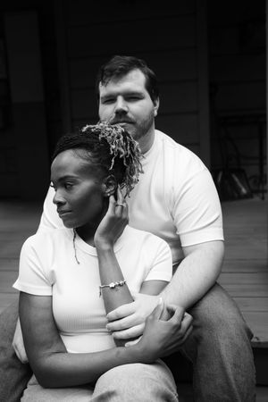 Black and white photo series showing an intimate moment between a couple sitting close together in casual clothing.