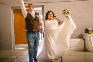 A bride twirls in her white wedding gown inside a bright indoor venue with white walls.