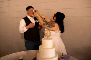 A couple cuts into their elegant white wedding cake during the reception celebration.