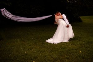 Romantic outdoor wedding photography session on a grassy lawn at dusk.