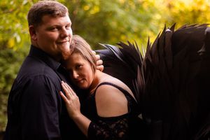 A couple embraces lovingly during a romantic outdoor photoshoot with golden sunlit foliage in the background.