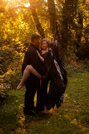 A romantic couple embraces in a golden sunlit forest setting during an autumn photoshoot.