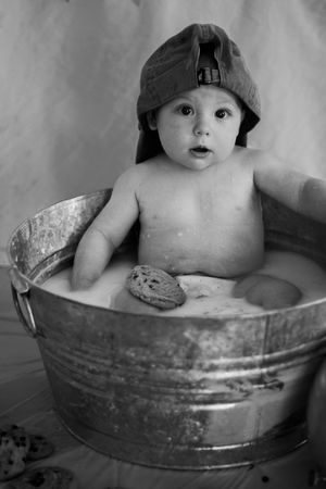 Black and white photo series showing a baby bathing in a vintage metal washtub with an expressive face.