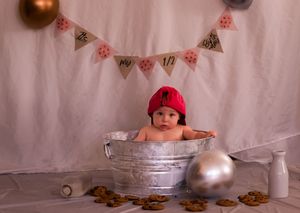 A row of copper and silver coins arranged in a line against a white fabric background with hanging decorative bunting.
