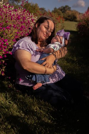 A tender outdoor scene in a garden with blooming pink flowers and soft sunlight filtering through the trees.