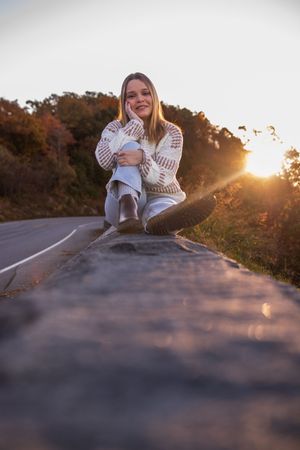 Someone sits on a winding mountain road at sunset creating a series of artistic silhouetted poses.