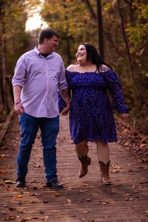 A couple walking on a leaf-covered path in autumn, showing their feet in a series of playful steps.