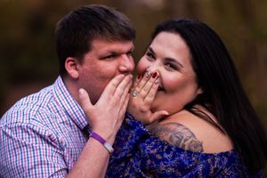 A couple shares a playful moment together during a photo session, with the woman wearing a blue dress.