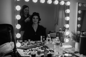 Makeup artist station with illuminated mirrors and cosmetics setup in professional dressing room.