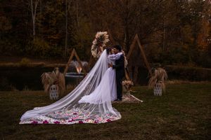 Romantic outdoor wedding ceremony setup with wooden arch and scattered rose petals at sunset.