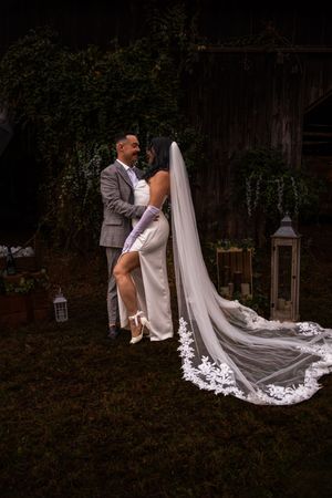 A couple shares an intimate moment with a flowing white cathedral veil during their outdoor garden wedding.