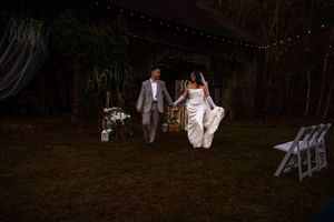 Evening wedding reception under string lights with wooden chairs and natural outdoor setting.