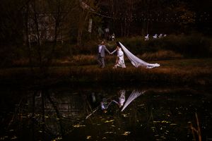 Romantic couple in white outfits pose together during sunset in a natural outdoor setting.