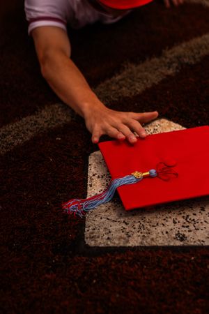 Hands pressing down on a red paper or card against a textured granite or marble countertop surface.