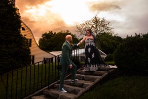 A couple sits together on stone steps at sunset creating a romantic silhouette against the orange sky.