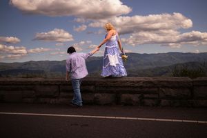 A group of people walking along a scenic mountain overlook with dramatic clouds in the sky.