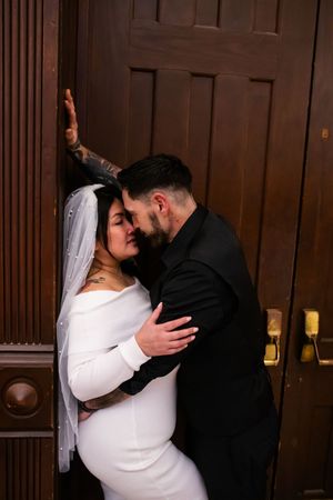 Romantic wedding couple shares intimate kisses against dark wooden doors in a series of candid moments.