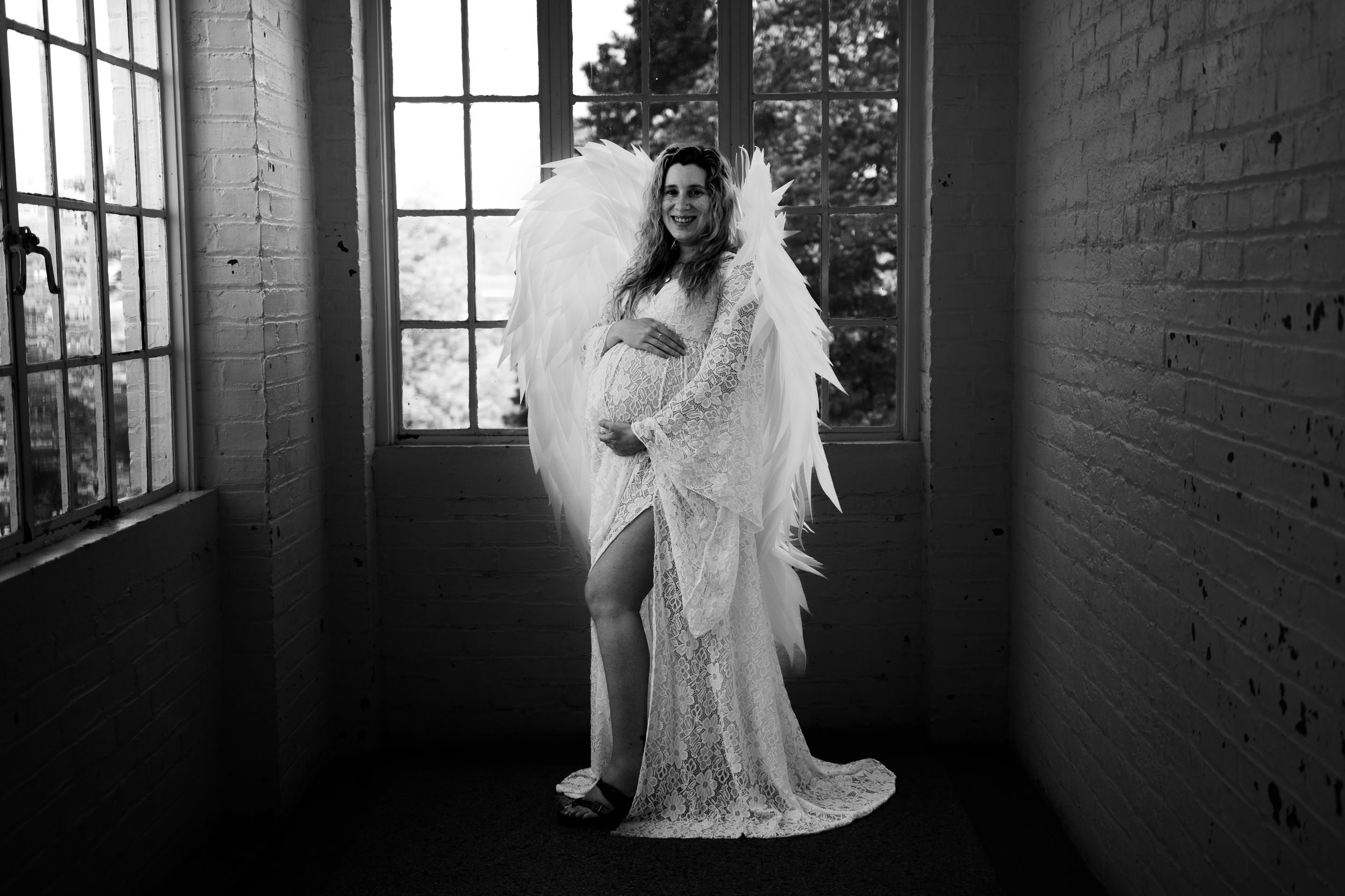 A black and white wedding photo series showing a bride in a flowing white dress posing in an industrial loft space.