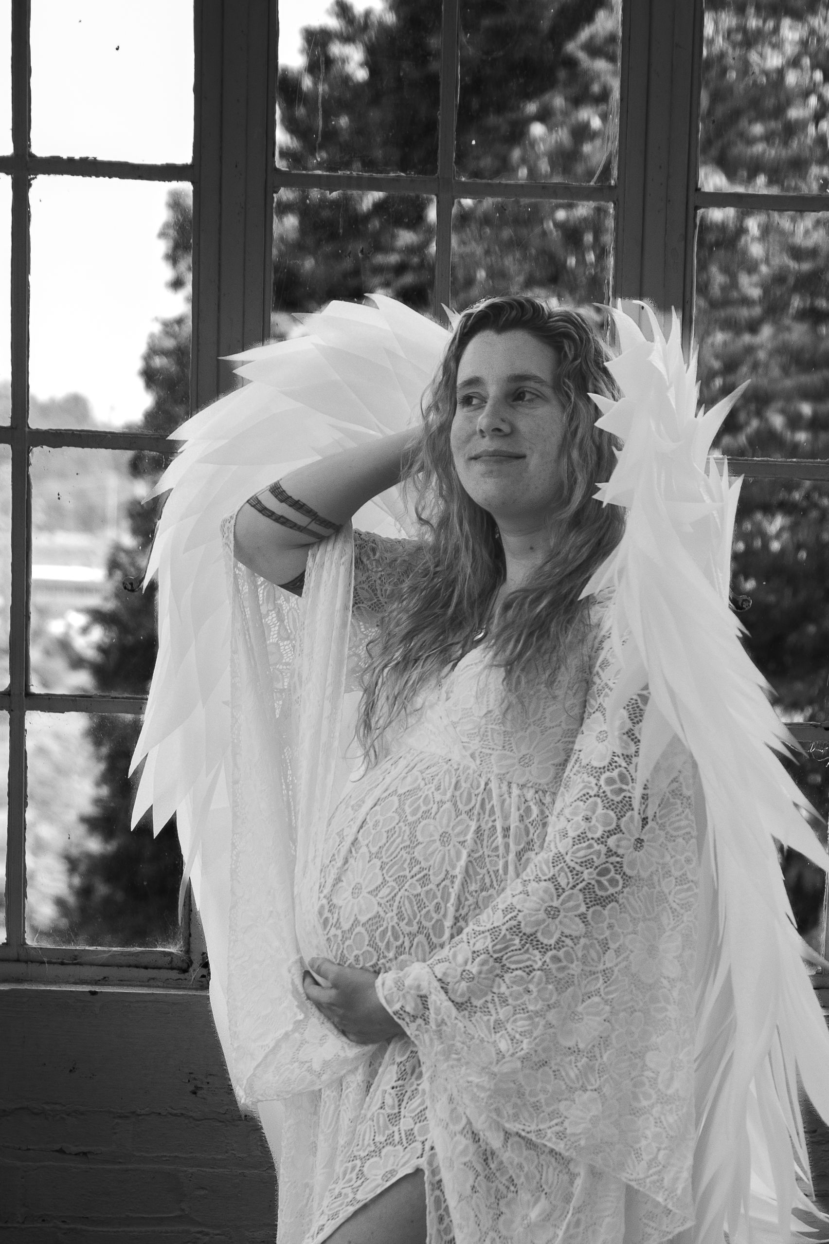 A person in a white lace dress and angel wings poses in multiple artistic black and white photos.