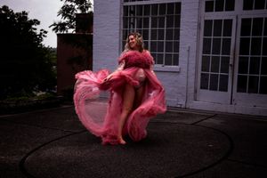 A pink fabric dress flows and twirls in motion against a dark background with white windows visible.