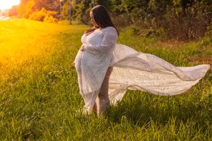 A flowing white lace dress billows in the breeze against a golden sunset in a grassy meadow.