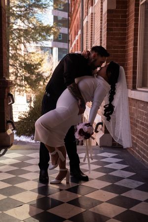Sequence of wedding poses on a checkered floor against brick walls with natural lighting.