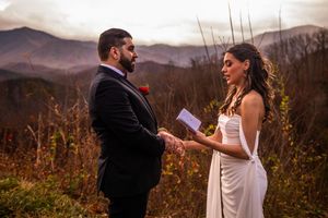 A couple shares an intimate moment during their wedding ceremony against a backdrop of autumn mountains.
