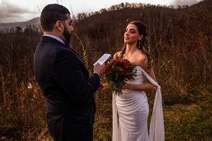 A couple exchanges vows during a scenic outdoor mountain wedding ceremony surrounded by fall foliage.