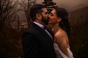 Romantic couple sharing intimate moments during sunset in a wooded outdoor setting.