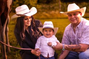 Family wearing white shirts and cowboy hats poses together outdoors during golden hour sunset.