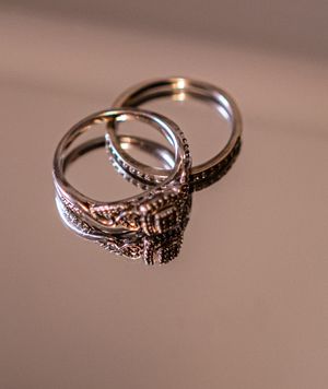 A close-up sequence showing a silver engagement ring with intricate details from multiple angles on a beige surface.