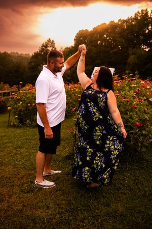 A romantic dance sequence captured in a rose garden with dramatic orange sunset lighting.