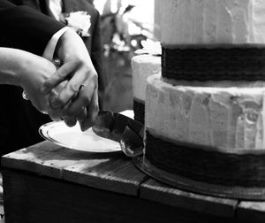 A series of black and white photos showing hands slicing and preparing a round layer cake.