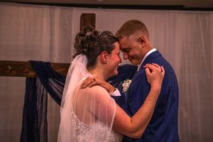 A couple shares an intimate moment during their wedding celebration in a softly lit indoor venue.