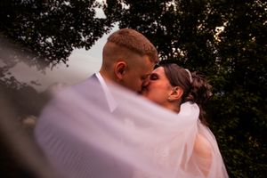 A romantic couple sharing an intimate moment during their wedding photoshoot outdoors at sunset.