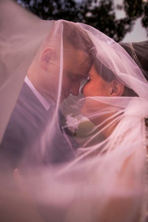 A romantic wedding moment captured through soft pink tulle veil creating an ethereal and dreamy effect.