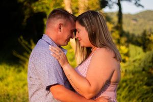 A romantic couple shares tender moments in a golden sunlit field during a summer photo session.